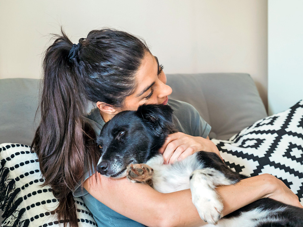 Woman hugging her dog on the couch.