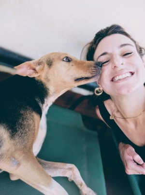 a woman smiles at the camera while a dog licks her face