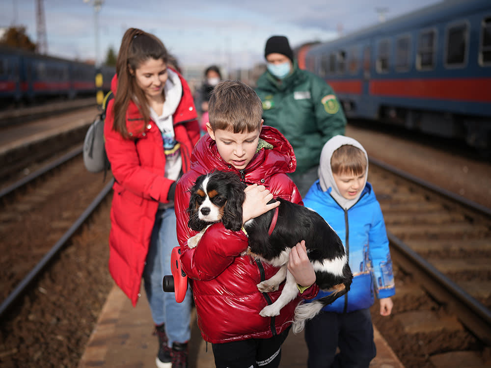 a boy in a red coat holds a dog