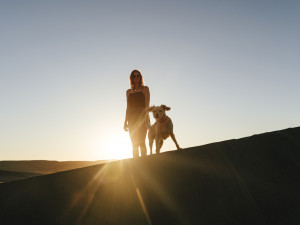 A woman walking with her dog at golden hour. 