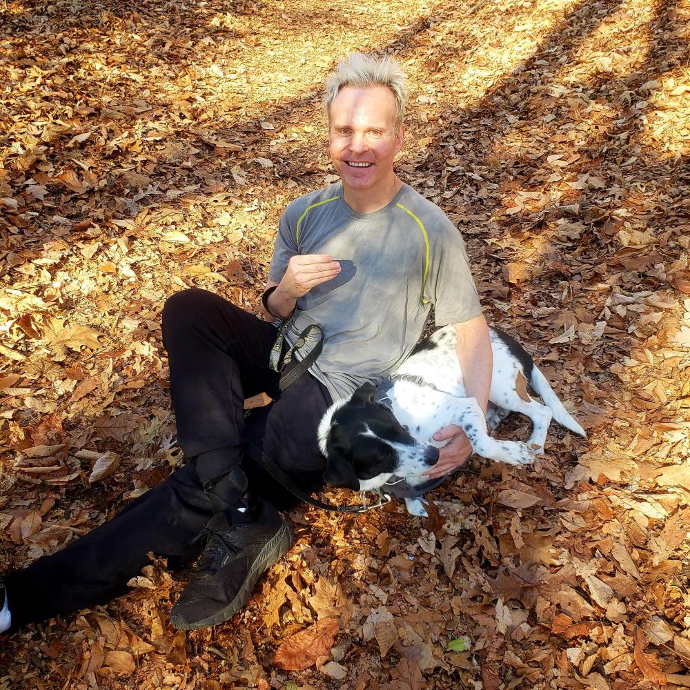 Sean Prichard sits in the leaves with his dog, Cliff