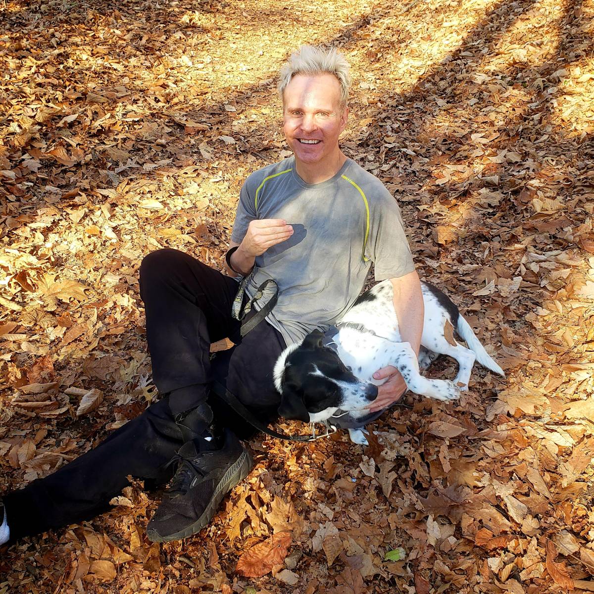 Sean Prichard sits in the leaves with his dog, Cliff