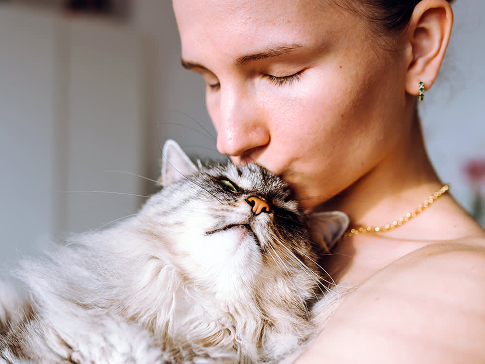 Woman cuddling her pet cat at home.