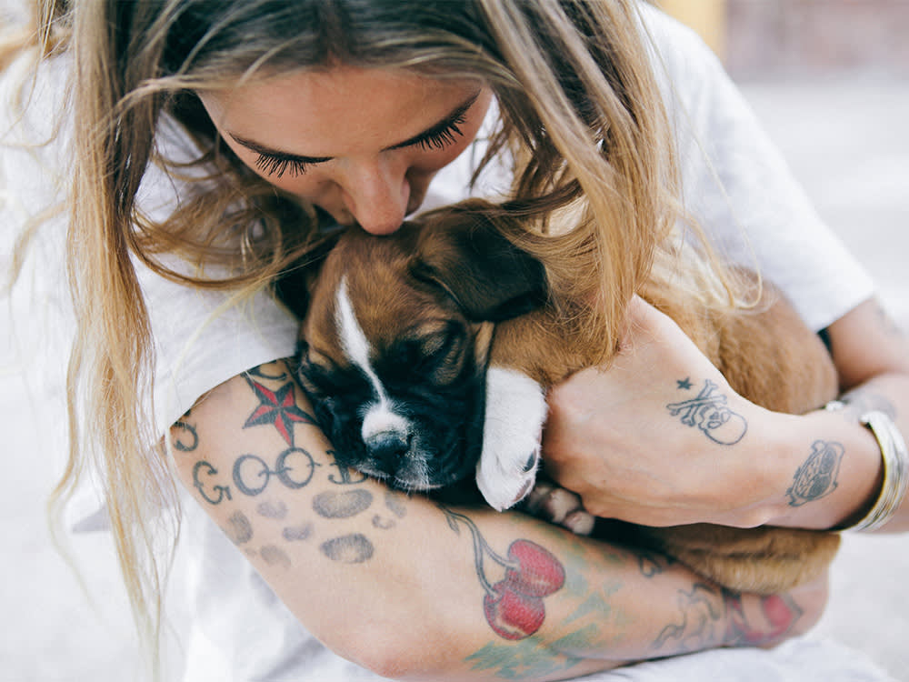 Tattooed woman holding a cute puppy.