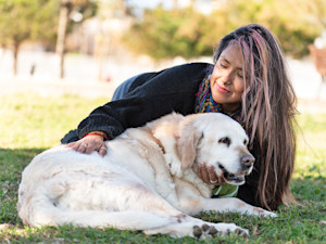 Woman petting a senior Golden Retriever dog outside.