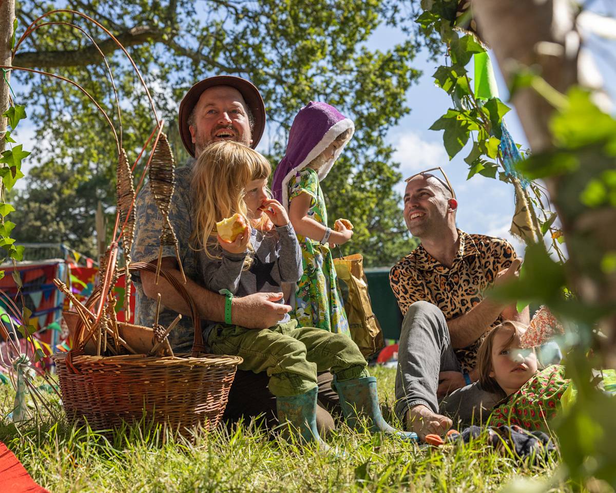 people and children sitting on grass at a festival