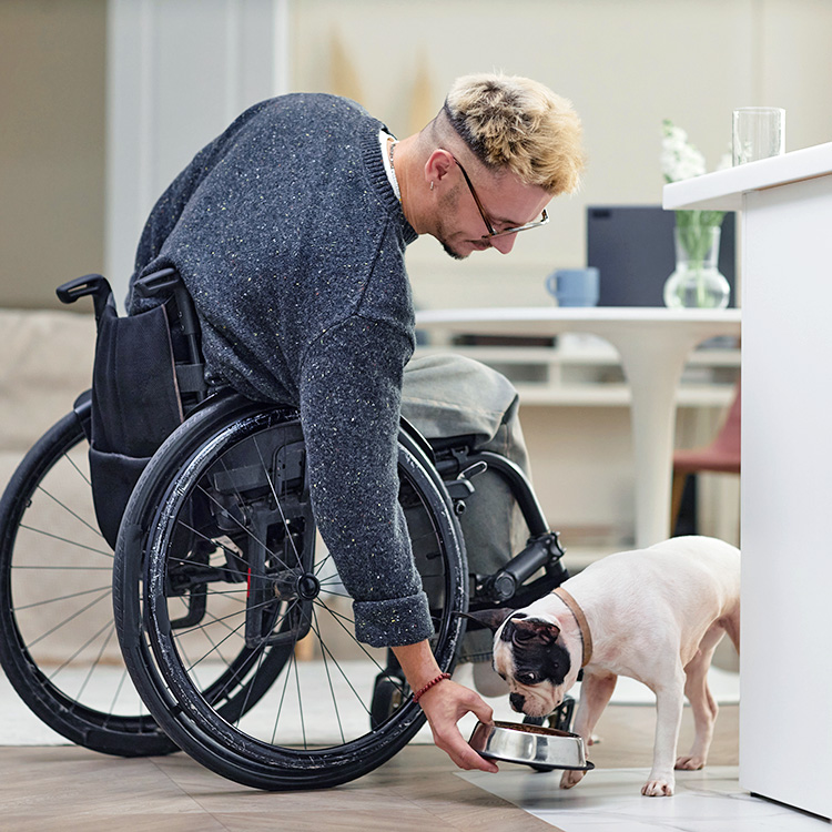 Man feeding his dog from a bowl at home.