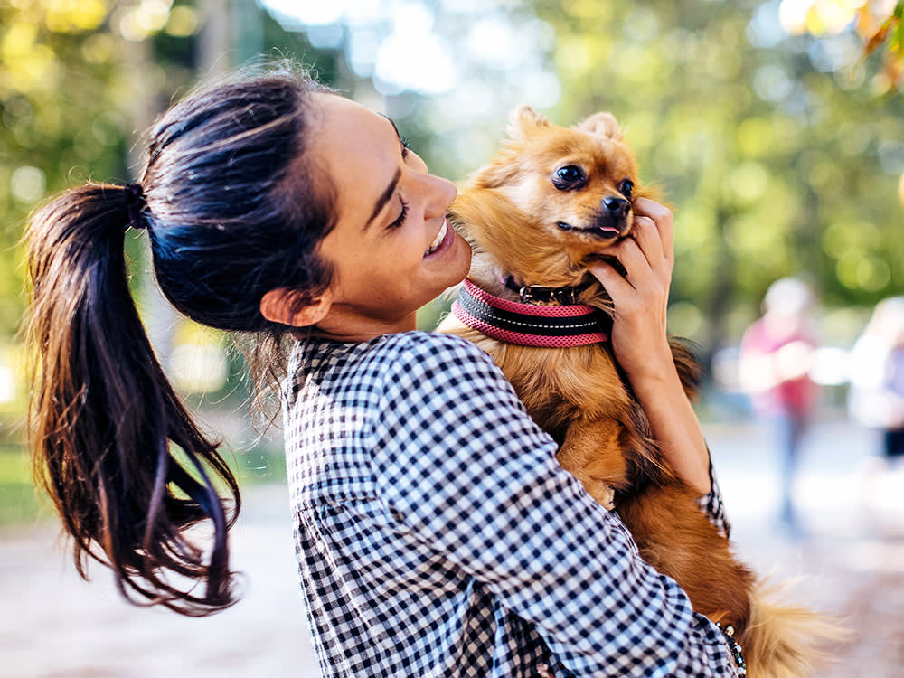 Woman picking up her dog outside.