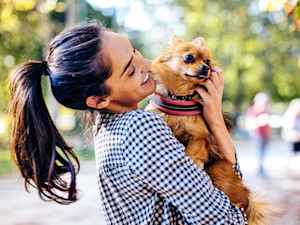 Woman picking up her dog outside.