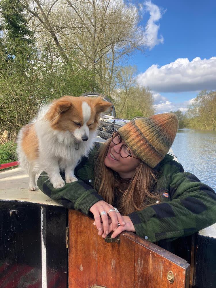 a woman with a bobble hat on a boat with her small dog