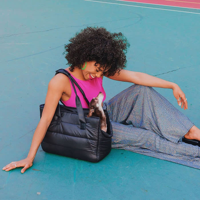 model sitting on ground with dog in black quilted tote