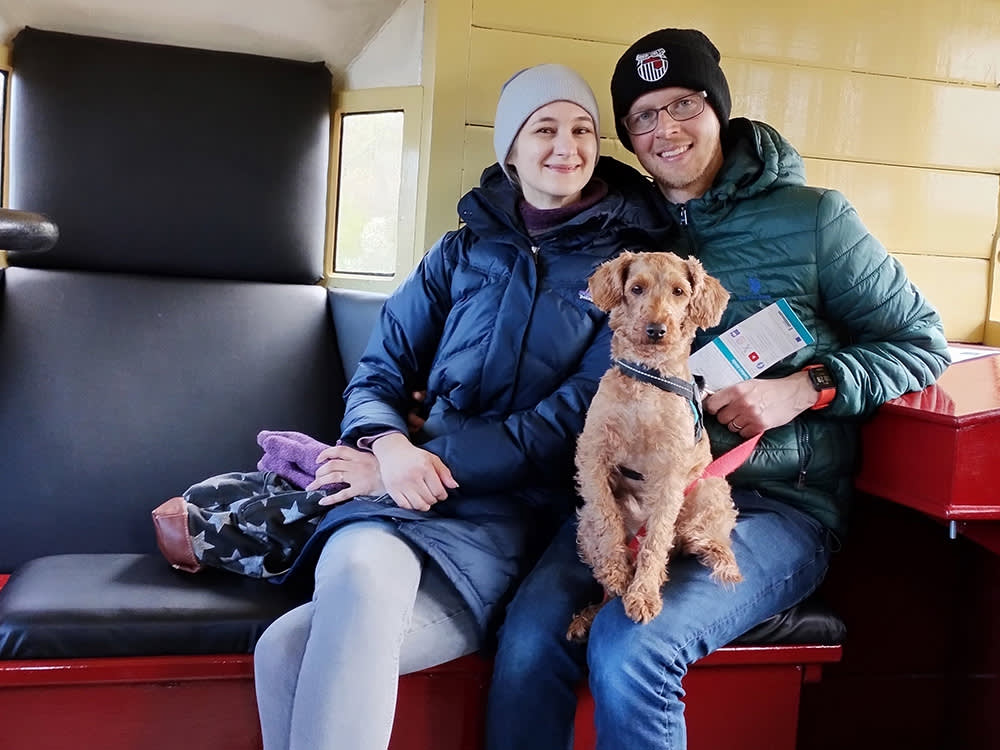 A couple sat with a red miniature poodle cross dog