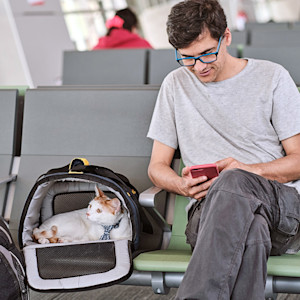 Man at an airport with his cat in a carrier.