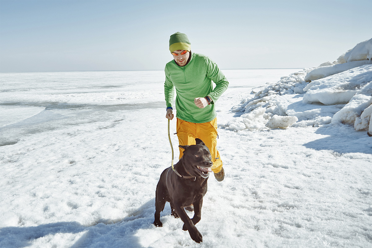a man running with his dog on a leash on ice