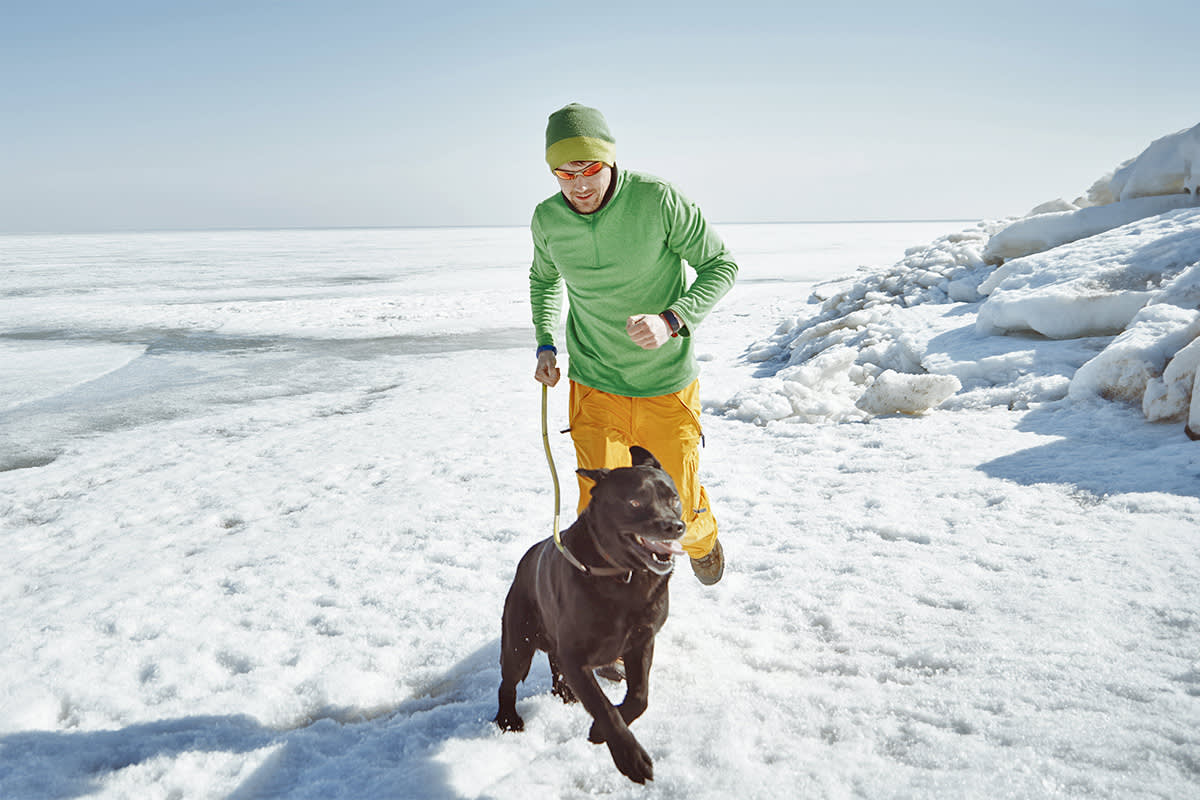 a man running with his dog on a leash on ice