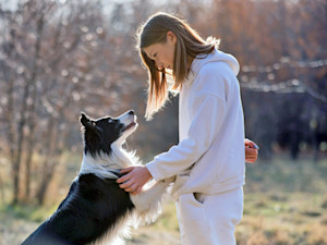 Woman looking at her dog intently outside.