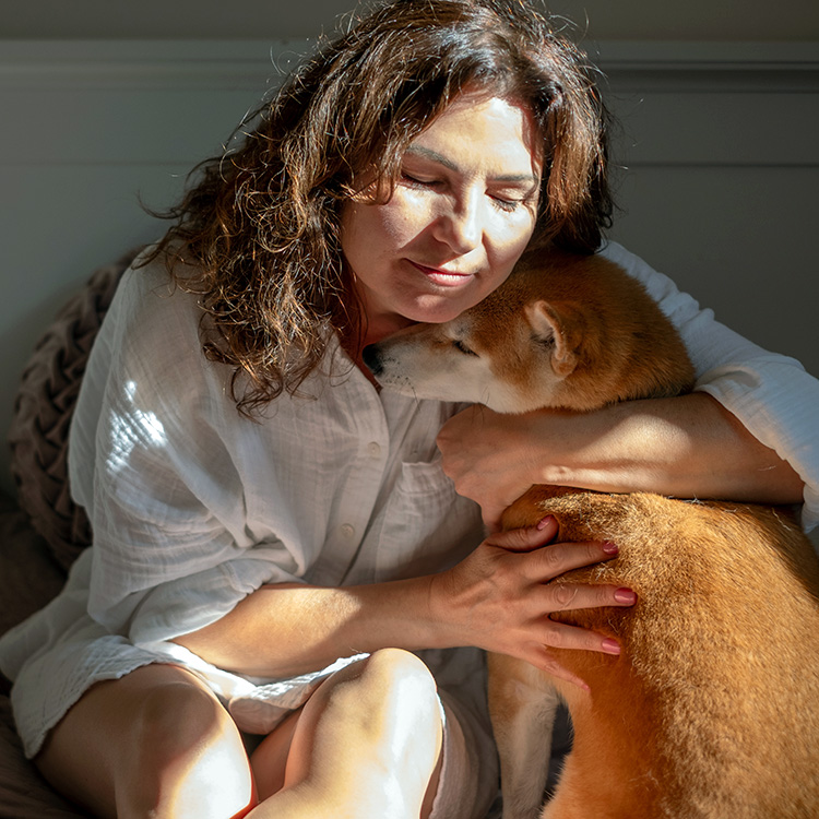 Woman snuggling her dog at home.