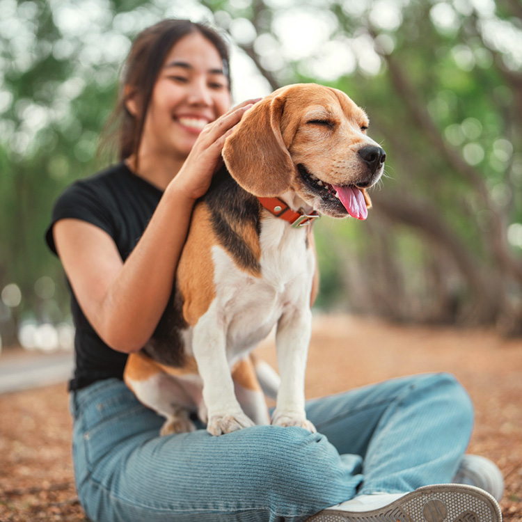 Women snuggling dog outside.