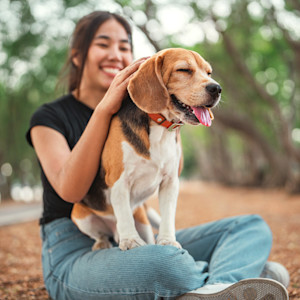 Women snuggling dog outside.