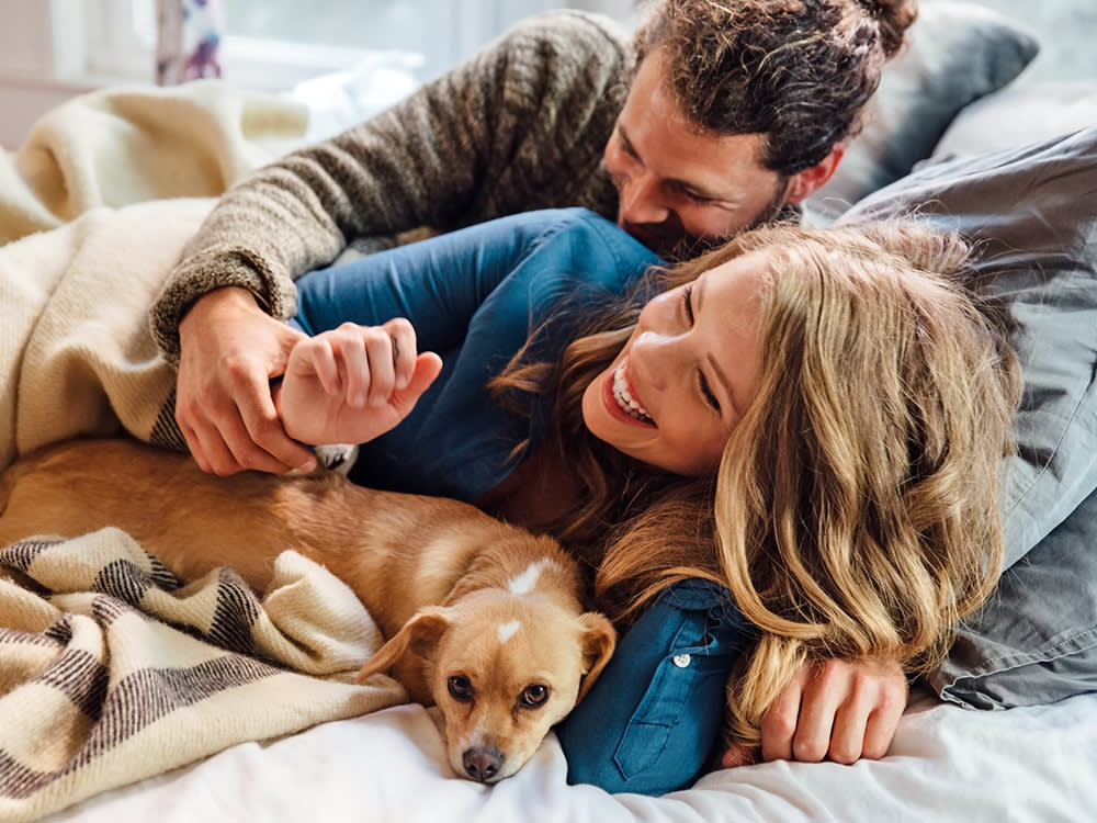 two people lying in bed with a dog