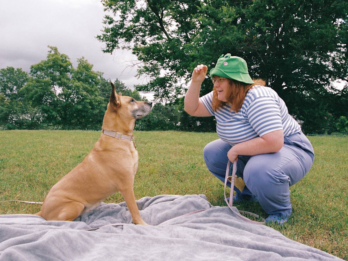 Corook bends down and shows Cubby a treat, while Cubby sits
