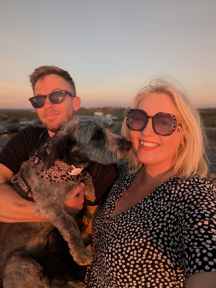 A picture of a man and a woman holding a grey dog