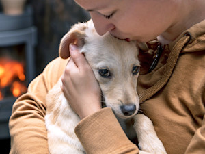 Woman snuggling her puppy in her arms.