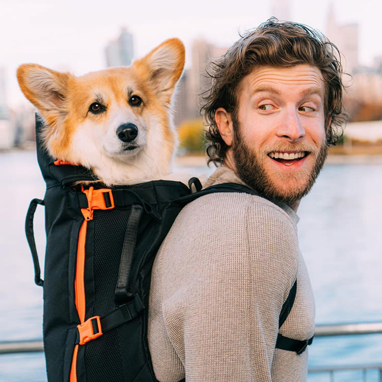 A man carrying a dog in a dog backpack. 