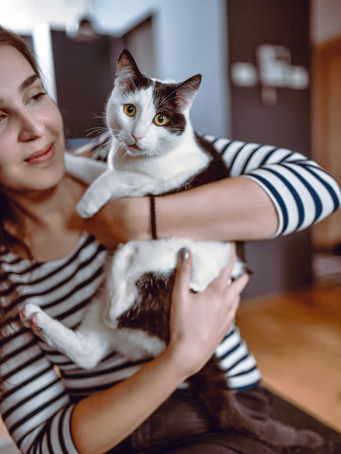 Woman holding her scared cat in her arms.