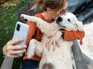 Woman taking a selfie with her cute Labrador dog outside.