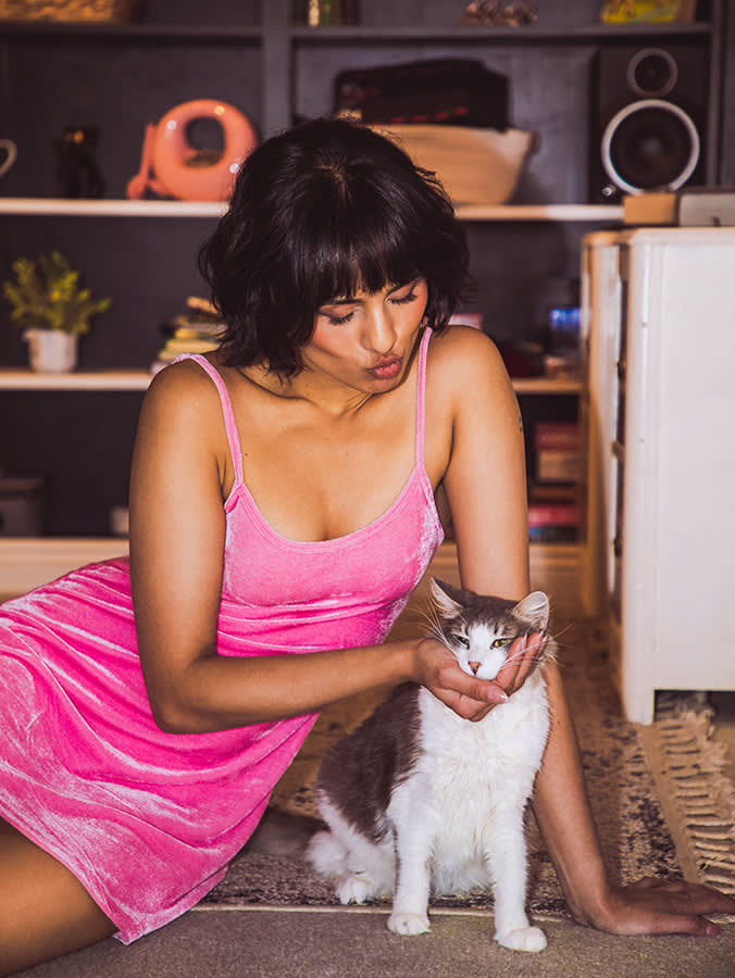 Aparna Brielle makes a kissy face at her cat, Oscar Wilde, while cupping his face in her hand.