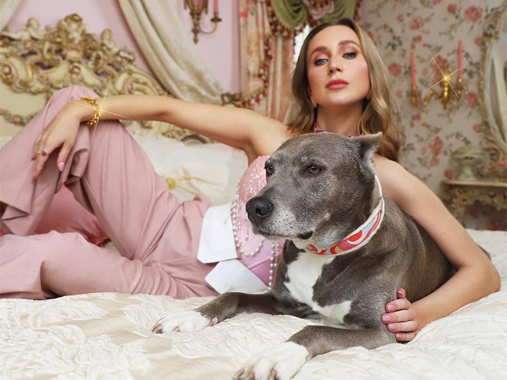 founder shelby with grey dog lounging on a bed