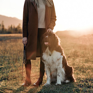 Woman standing with her dog outside in a field.