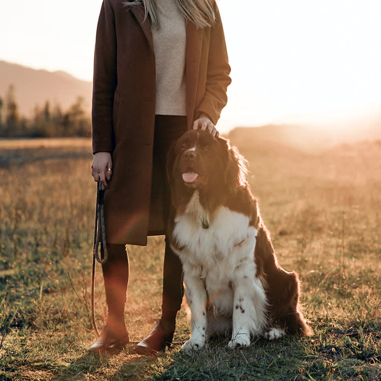 Woman standing with her dog outside in a field.