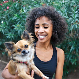 Woman holding her dog outside.