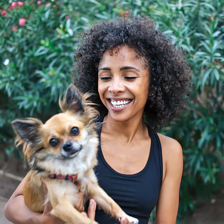 Woman holding her dog outside.