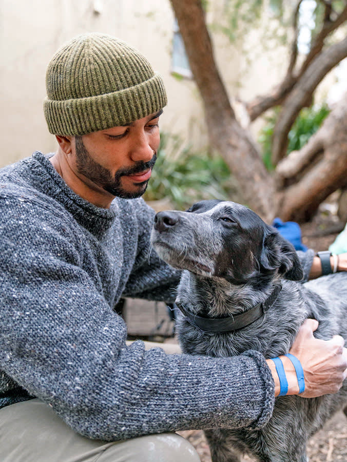 Man cuddling his dog outside.
