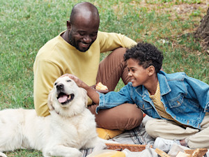 Father and son have a picnic with their Lab dog.
