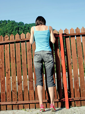 Woman looking over the fence for her lost cat.