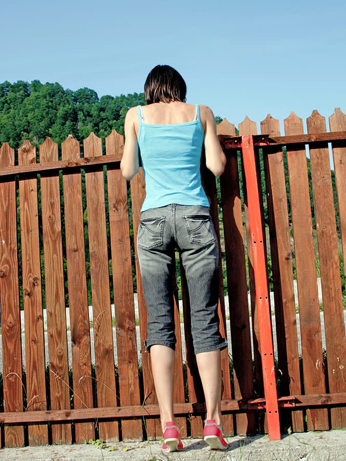 Woman looking over the fence for her lost cat.