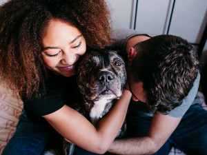 Couple hugs their merle Boxer