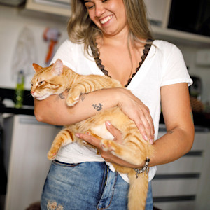 Woman holding her orange cat at home.