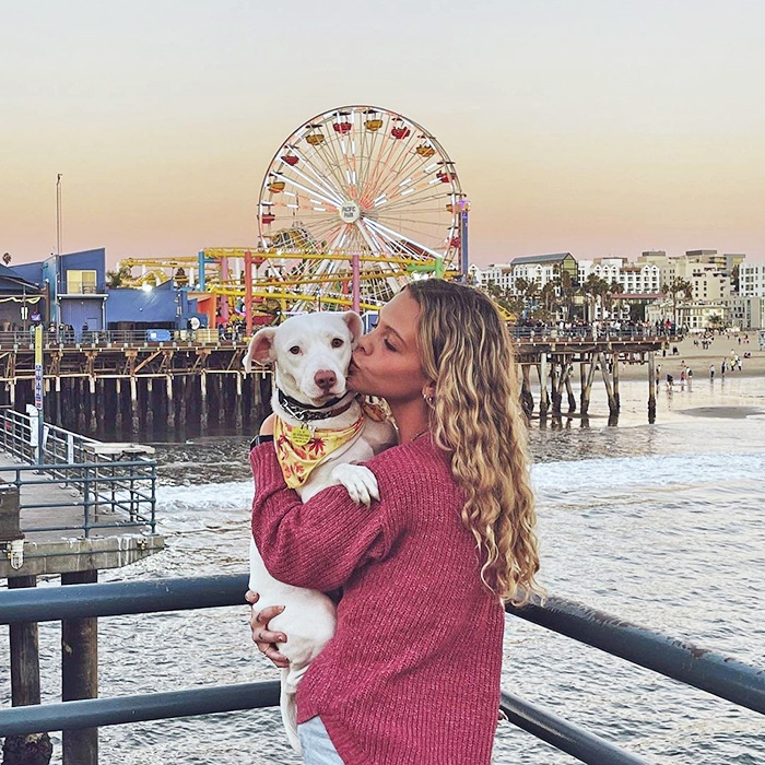 A dog parent cuddling their pup at Santa Monica Pier