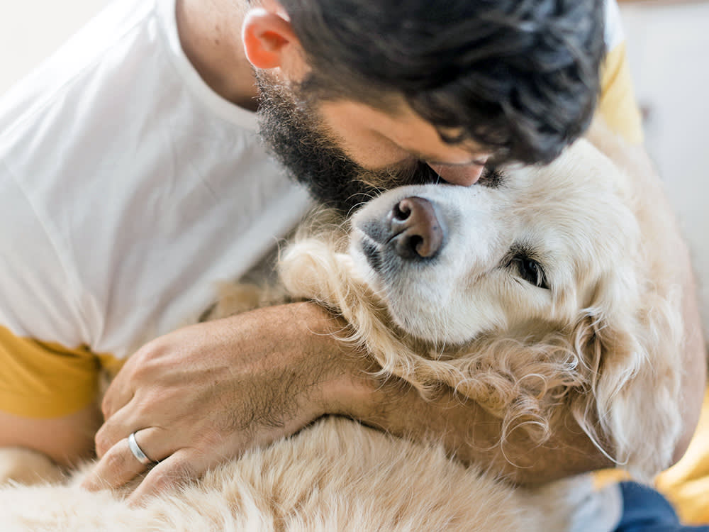 Man holding his senior dog in his arms.
