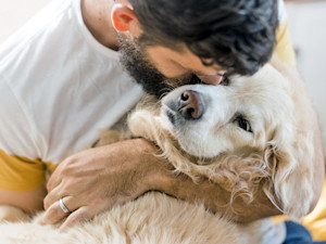 Man holding his senior dog in his arms.