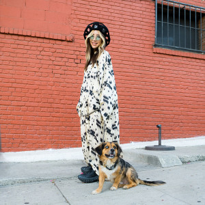 A portrait of a woman smiling with her dog outside. 