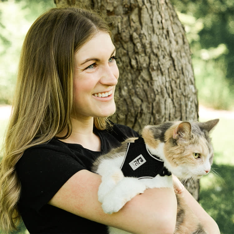 Angela Rafuse smiling while holding her rescue cat near a tree outside 