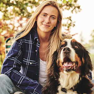 Blonde woman looking at the camera next to her dog