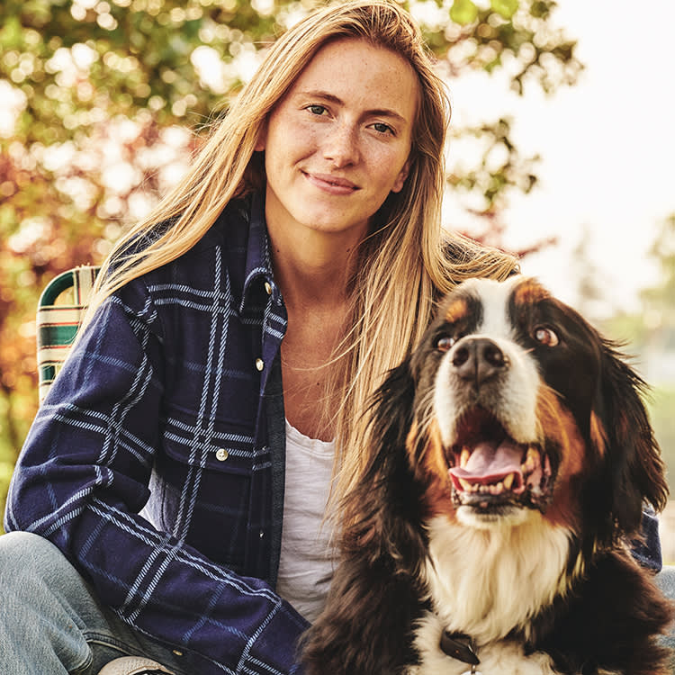 Blonde woman looking at the camera next to her dog