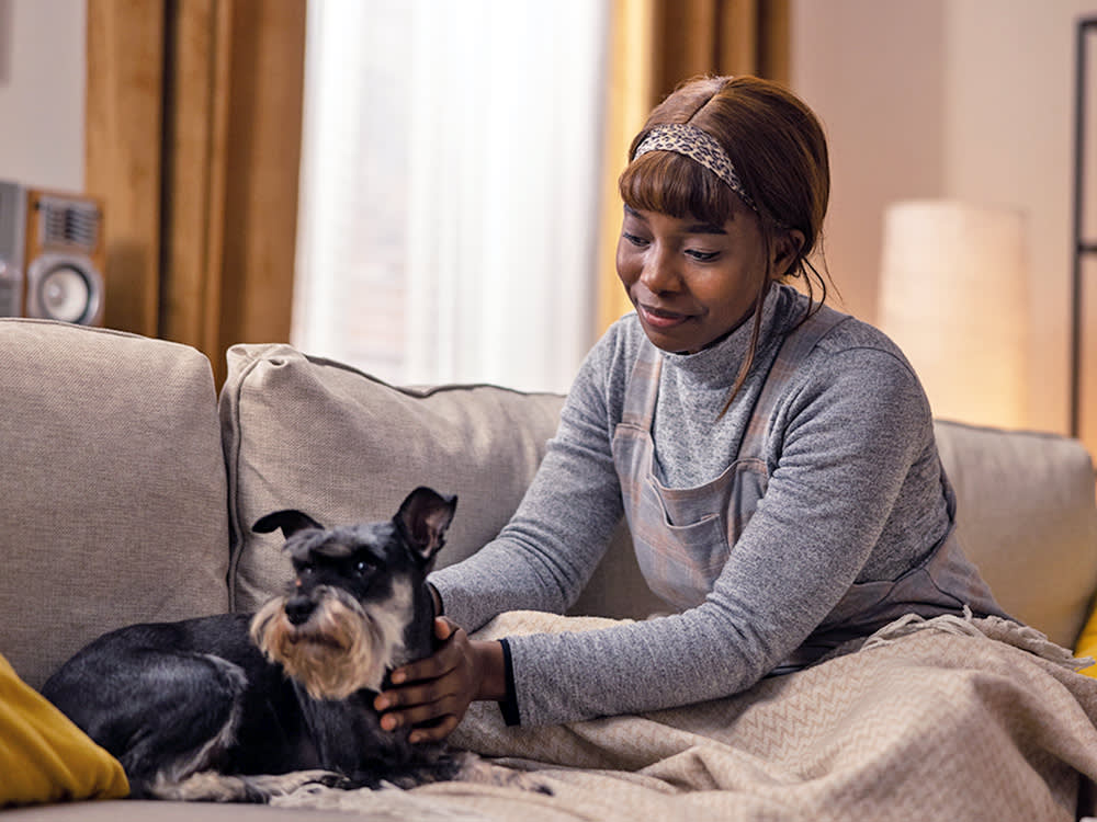 Woman comforting her small black dog on the couch.